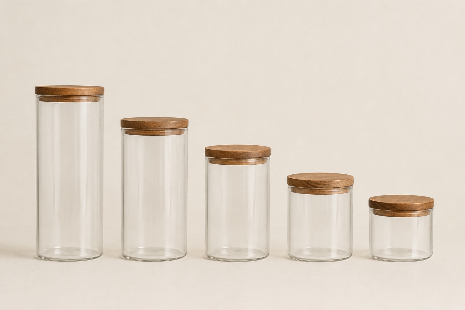 The five glass jars standing in a row, tallest to shortest, each with a round acacia lid